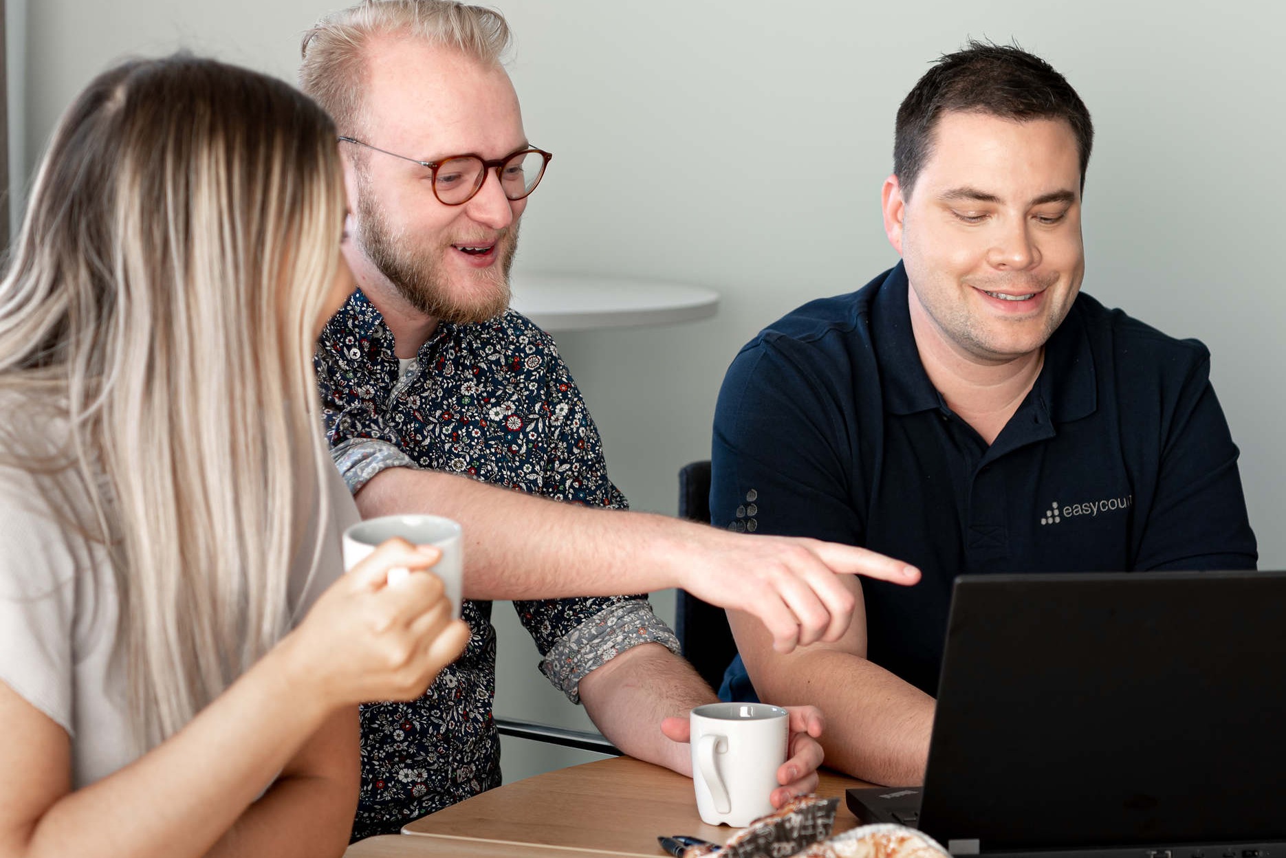 Tre medarbetare på Easycount samtalar vid en bärbar dator